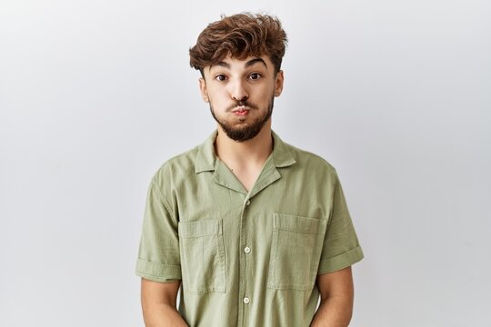 Young arab doctor man standing over isolated background puffing cheeks with funny face. mouth inflated with air, crazy expression.