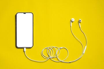 Top View, blank screen of new smartphone or mobile connects to earphones cable on yellow background.