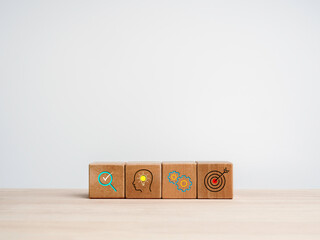 Business strategy and action plan concept. Four wooden cube blocks with business strategy icon symbols on a wooden table on white background with copy space.
