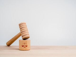 A wooden judge gavel with words, ethics, respect, honesty, and integrity with the soundboard with...