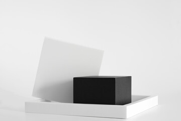 Black podium with white simple geometric forms on the white background. Podium for product, cosmetic presentation. Creative mock up. Pedestal or platform for beauty products.