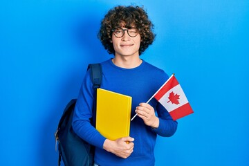 Handsome young man exchange student holding canada flag winking looking at the camera with sexy...