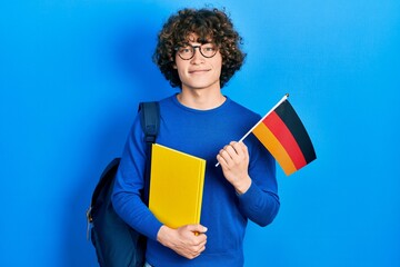 Handsome young man exchange student holding germany flag smiling with a happy and cool smile on face. showing teeth.