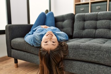 Young chinese girl smiling happy lying on the sofa at home.