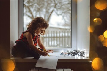 Beautiful atmospheric Christmas photo. A girl writes a letter to Santa Claus. Photo with a beautiful bokeh.