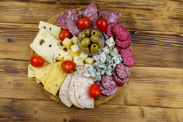 Antipasti platter with olives, cherry tomatoes, assortment of italian salami and cheese on a wooden table. Top view