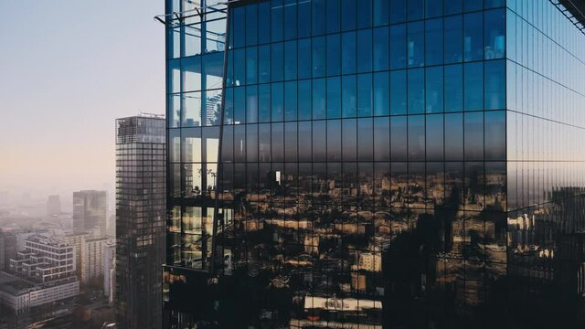 Modern business districtcity glass skyscrapers drone zoom in close to the buildings. Skyscraper in the big city top view during the sunrise when first sun rays are going through the glass windows.