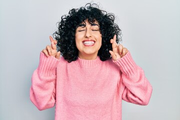 Young middle east woman wearing casual clothes gesturing finger crossed smiling with hope and eyes closed. luck and superstitious concept.