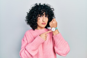 Young middle east woman wearing casual clothes in hurry pointing to watch time, impatience, looking...