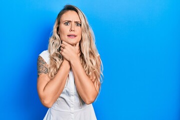 Fototapeta premium Beautiful young blonde woman wearing casual white shirt shouting and suffocate because painful strangle. health problem. asphyxiate and suicide concept.