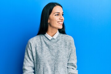 Young hispanic woman wearing casual clothes looking away to side with smile on face, natural expression. laughing confident.