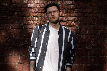 young handsome man with glasses near brick wall