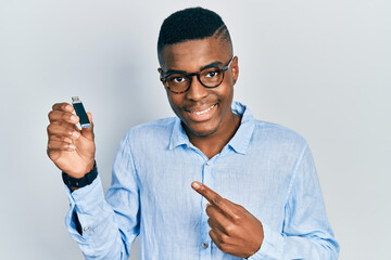 Young african american man holding removable memory usb smiling happy pointing with hand and finger