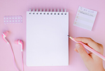 Notepad, headphones and pencil on a pink background. Online education, distance learning.Completing school homework.Flat lay