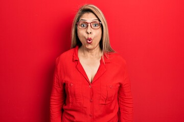 Middle age hispanic woman wearing casual clothes and glasses scared and amazed with open mouth for...