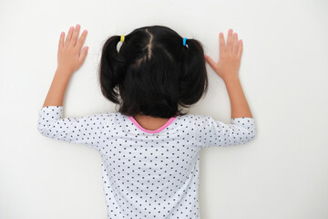 Back view of kid facing wall and put her hands up - obrazy, fototapety, plakaty