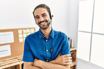 Young hispanic man with beard wearing call center agent headset at the office happy face smiling...