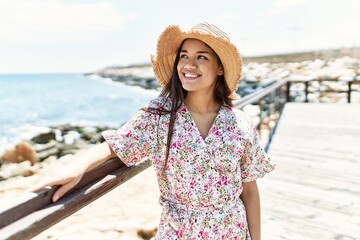 Fototapeta premium Young latin girl smiling happy wearing summer hat at the beach.