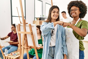 Group of young draw students drawing at art studio. Two woman smiling happy bumb fists.