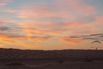 Vol en paramoteur au dessus des dunes dans le désert, coucher de soleil. Tunisie.