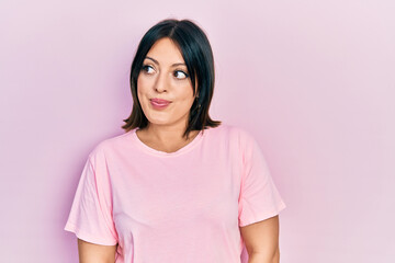 Fototapeta premium Young hispanic woman wearing casual pink t shirt smiling looking to the side and staring away thinking.