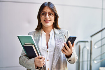 Young hispanic businesswoman smiling happy using smartphone at the city.