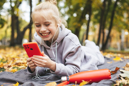 Gen z teenage girl using smartphote outdoors in autumn time.