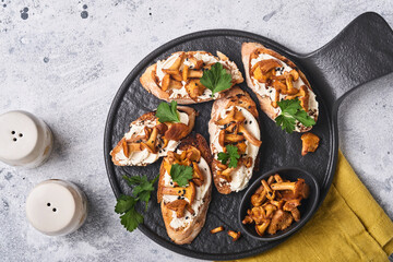 Chanterelle sandwiches with cheese. Open faced sandwich with creamy cheese, seasonings and pepper and fresh parsley on an old wooden background. Mock up. Top view.