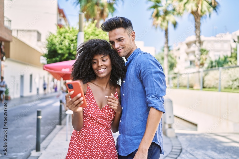 Canvas Prints Man and woman couple smiling confident using smartphone at street