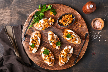 Chanterelle sandwiches with cheese. Open faced sandwich with creamy cheese, seasonings and pepper and fresh parsley on an old wooden background. Mock up. Top view.