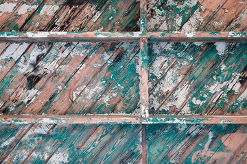 Peeling teal and white paint on wood boards laid diagonally