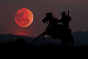 The Cowboy silhouette on horseback with blood moon