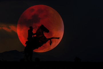 The Cowboy silhouette on horseback with blood moon