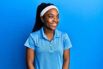 African american woman with braided hair wearing tennis player uniform looking to side, relax...