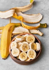 Photo of banana slices in a bowl on a concrete surface