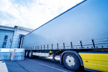 Large trucks near warehouse against blue sky background