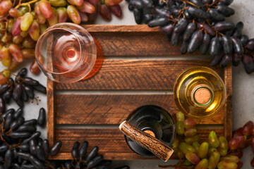 Two Wine bottles with grapes and wineglasses on old gray concrete table background with copy space. Red wine with a vine branch. Wine composition on rustic background. Mock up.