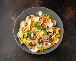 White shell clams in Garlic and parsley white wine sauce tagliatelle pasta served with cherry tomatoes and parmesan cheese