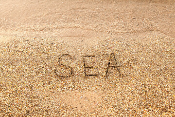 The word Sea is written on the sandy seashore