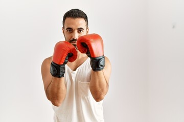 Young hispanic man boxing over isolated white background