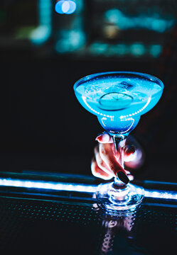 close-up of woman bartender hand holds cold blue cocktail Blue Lagoon in bar