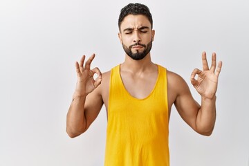 Young handsome man with beard standing over isolated background relax and smiling with eyes closed doing meditation gesture with fingers. yoga concept.