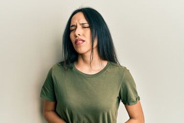 Obraz premium Young hispanic girl wearing casual t shirt with hand on stomach because nausea, painful disease feeling unwell. ache concept.