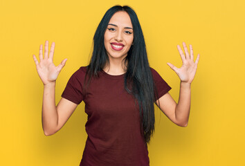Young hispanic girl wearing casual t shirt showing and pointing up with fingers number ten while smiling confident and happy.