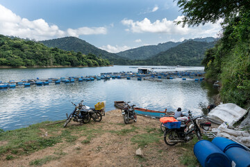 Dramatic image of a tilapia fish farm high in the Caribbean mountains of the Dominican Republic with hills and cloudy skies in the background.