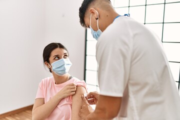 Young nurse man putting band aid on woman arm at the clinic.