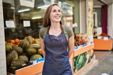 Young blonde woman smiling happy wearing apron at fruit store