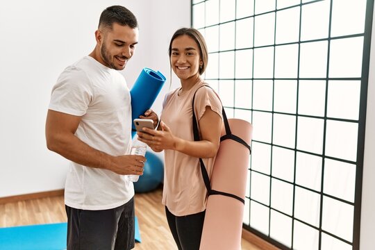 Latin man and woman couple wearing sportswear using smartphone at sport center