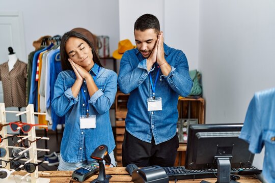 Young interracial people working at retail boutique sleeping tired dreaming and posing with hands together while smiling with closed eyes. - Powered by Adobe