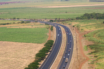 An Aerial View of a Freeway in Hawaii with Clear Definition of the Roadway's Black Asphalt Strips and Green Agricultural Landscape